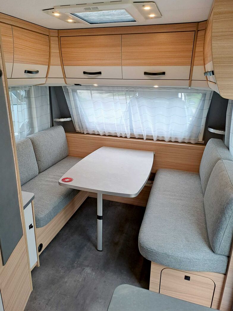Le chaleureux décor bois donne une impression de confort, tandis que les surfaces en contraste gris-beige et le tissu gris des coussins ajoutent une touche de modernité.