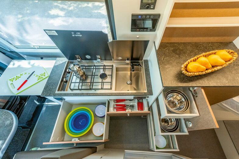 Bloc cuisine avec tiroirs, plan de travail, évier et plaque de cuisson à deux feux.