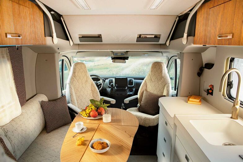 Chaleureux malgré des dimensions compactes : l’espace à vivre de l’Oasi 540.1 avec dînette en L, sièges de cabine pivotants, table coulissante et bloc-cuisine.